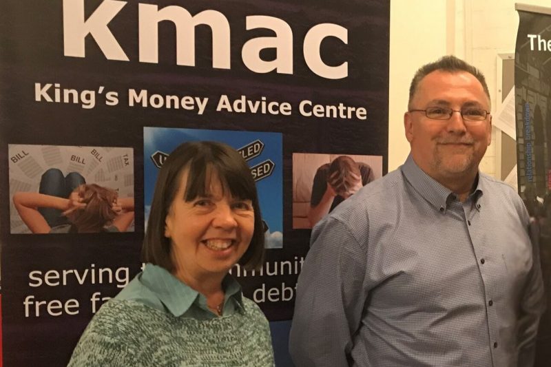 two people stand in front of KMAC banner smiling