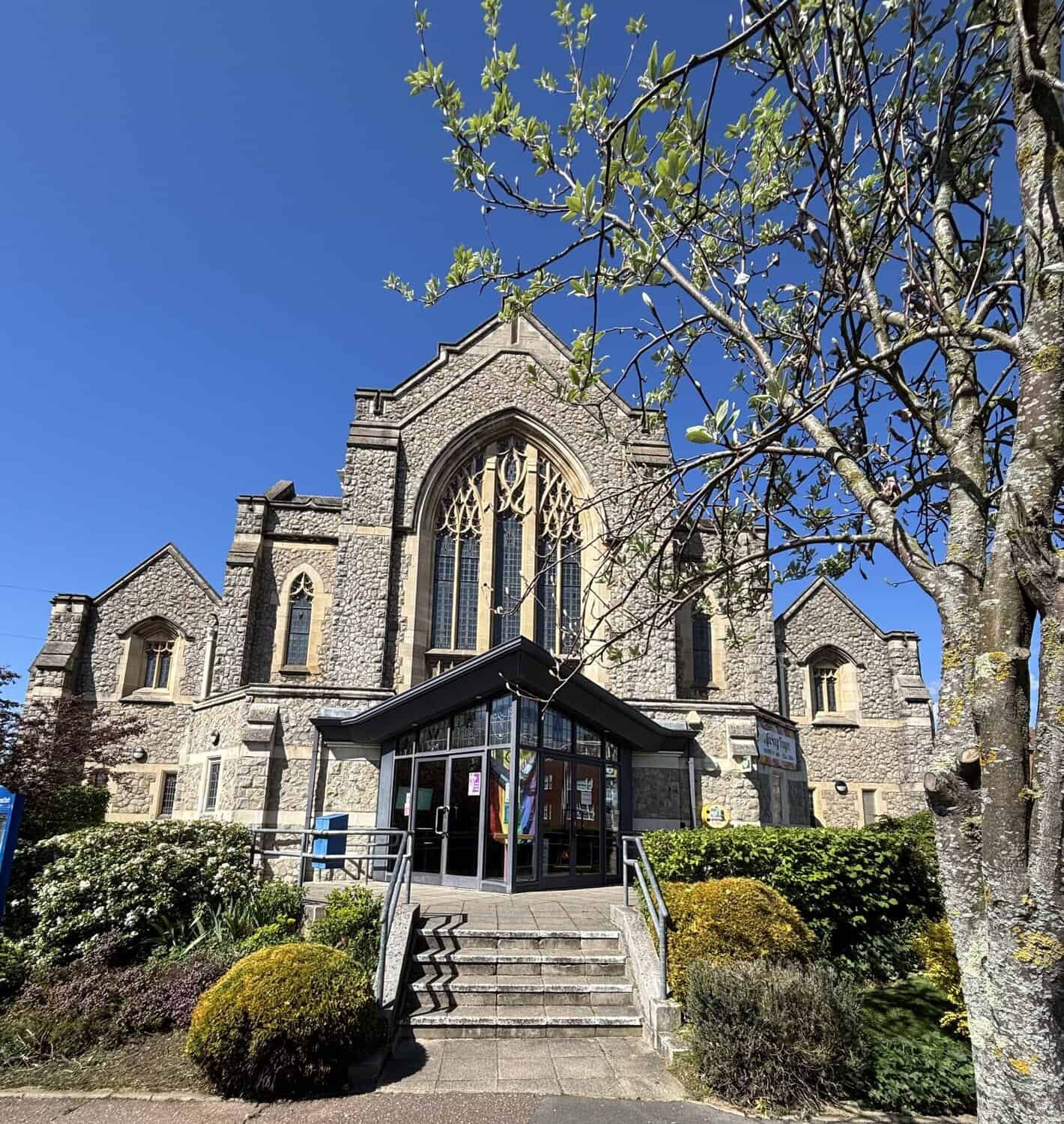 Kings Road United Reformed Church building entrance with blue sky behind and shrubs in the foreground